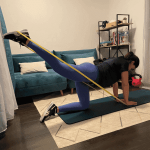 Femme réalisant un exercice de renforcement musculaire avec élastique, coaching sportif à domicile à Cannes